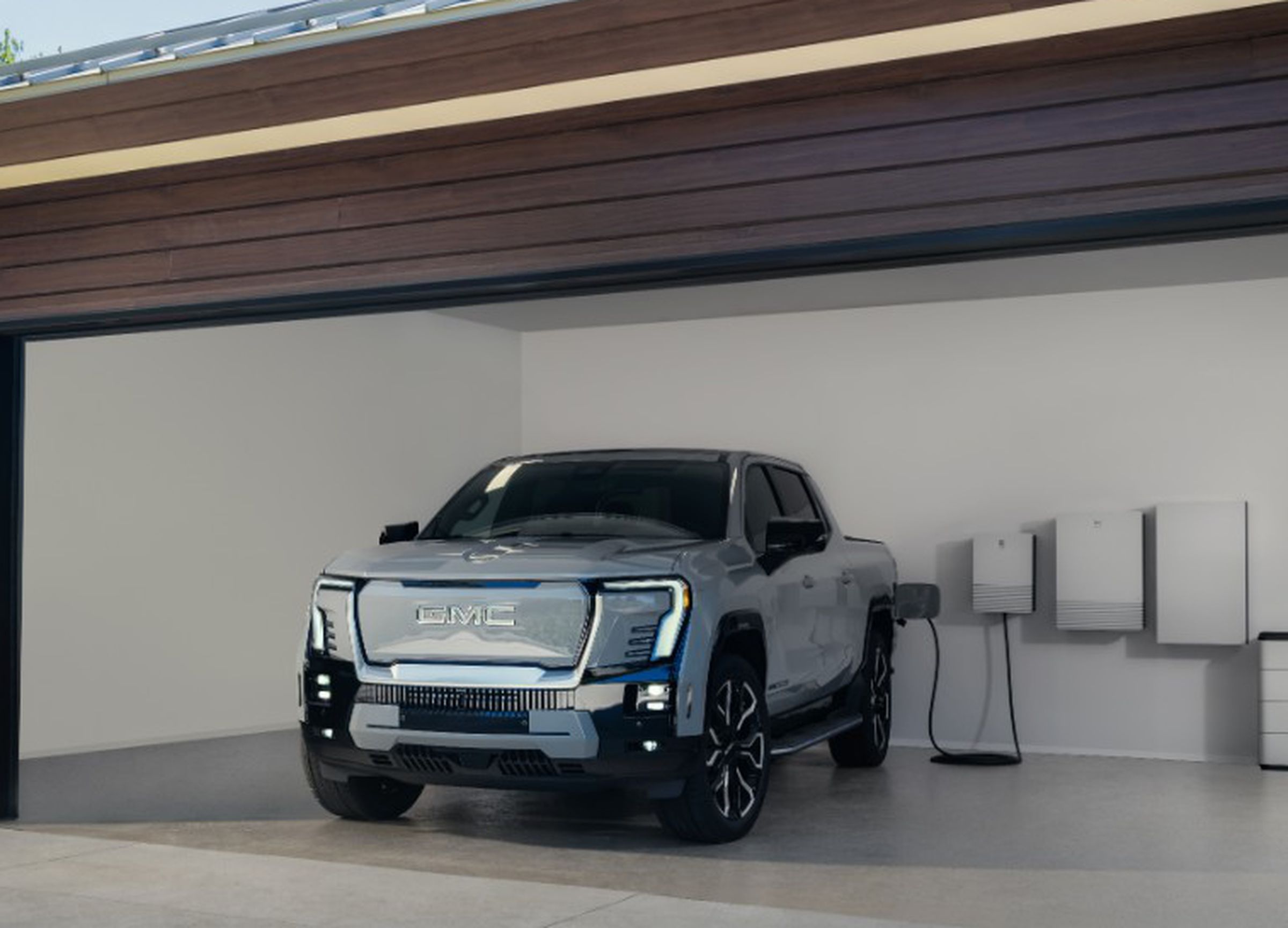 truck in garage with door open, battery system and ev charger plugged in, lake in the background outside