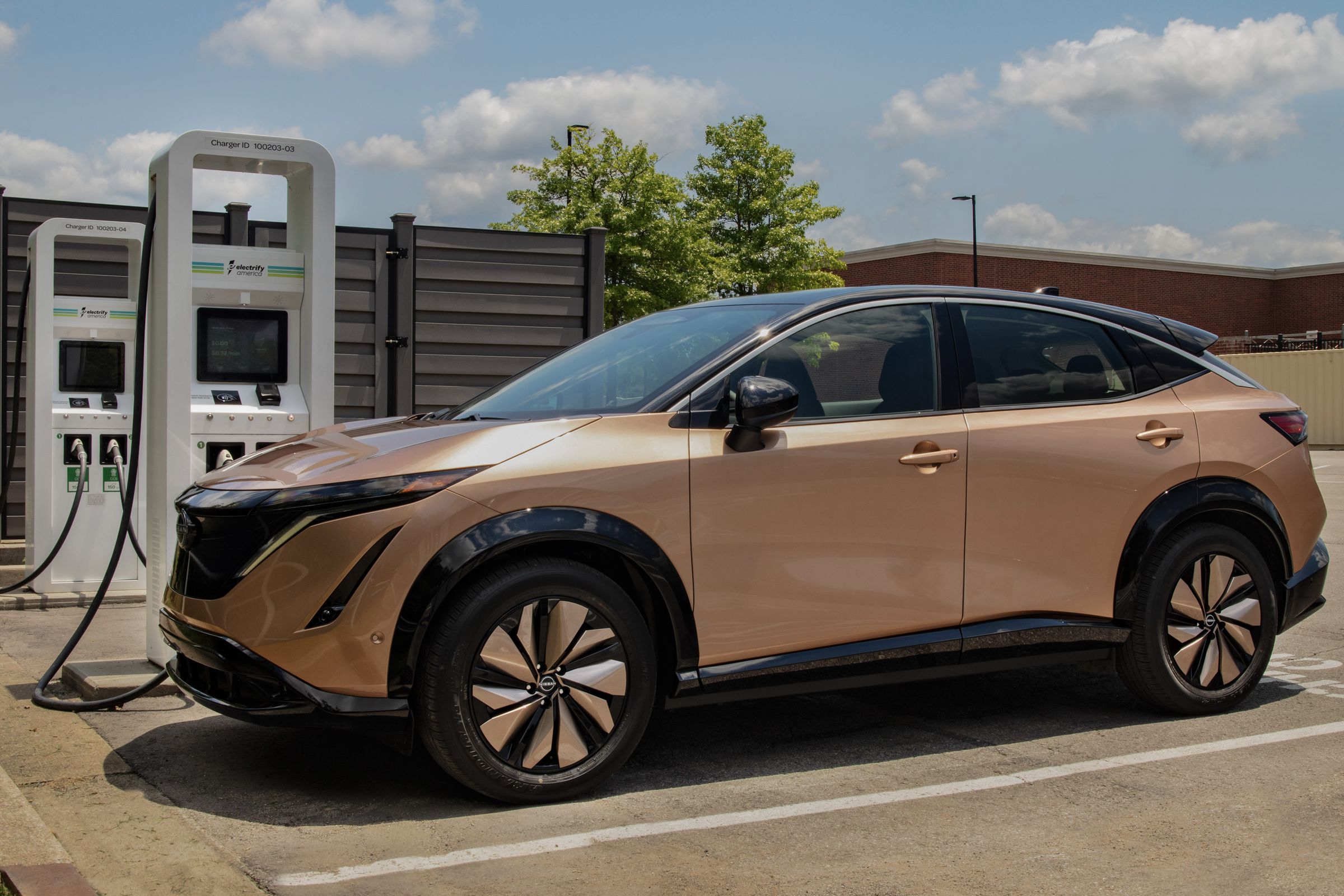 a bronze Nissan ariya suv parked at a charging station 