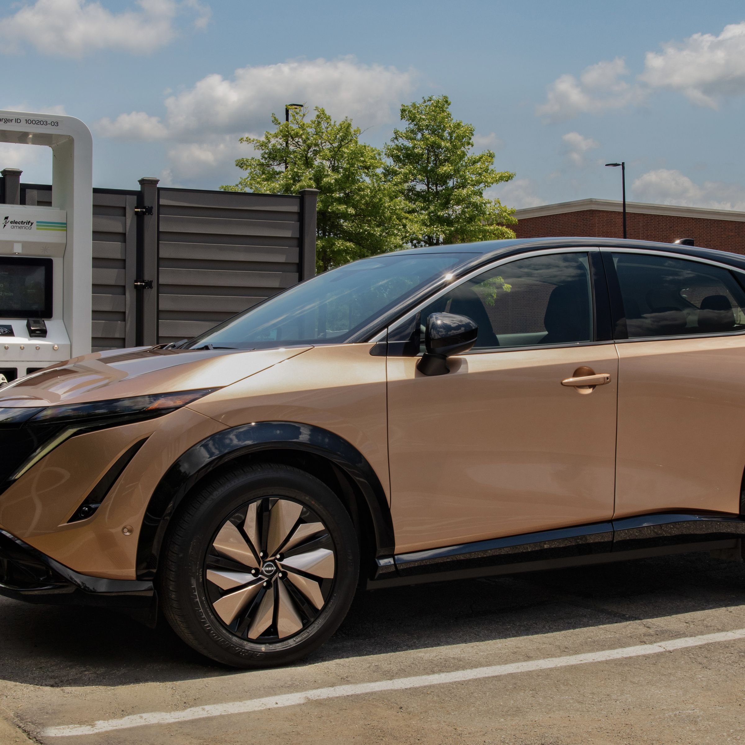 a bronze Nissan ariya suv parked at a charging station 