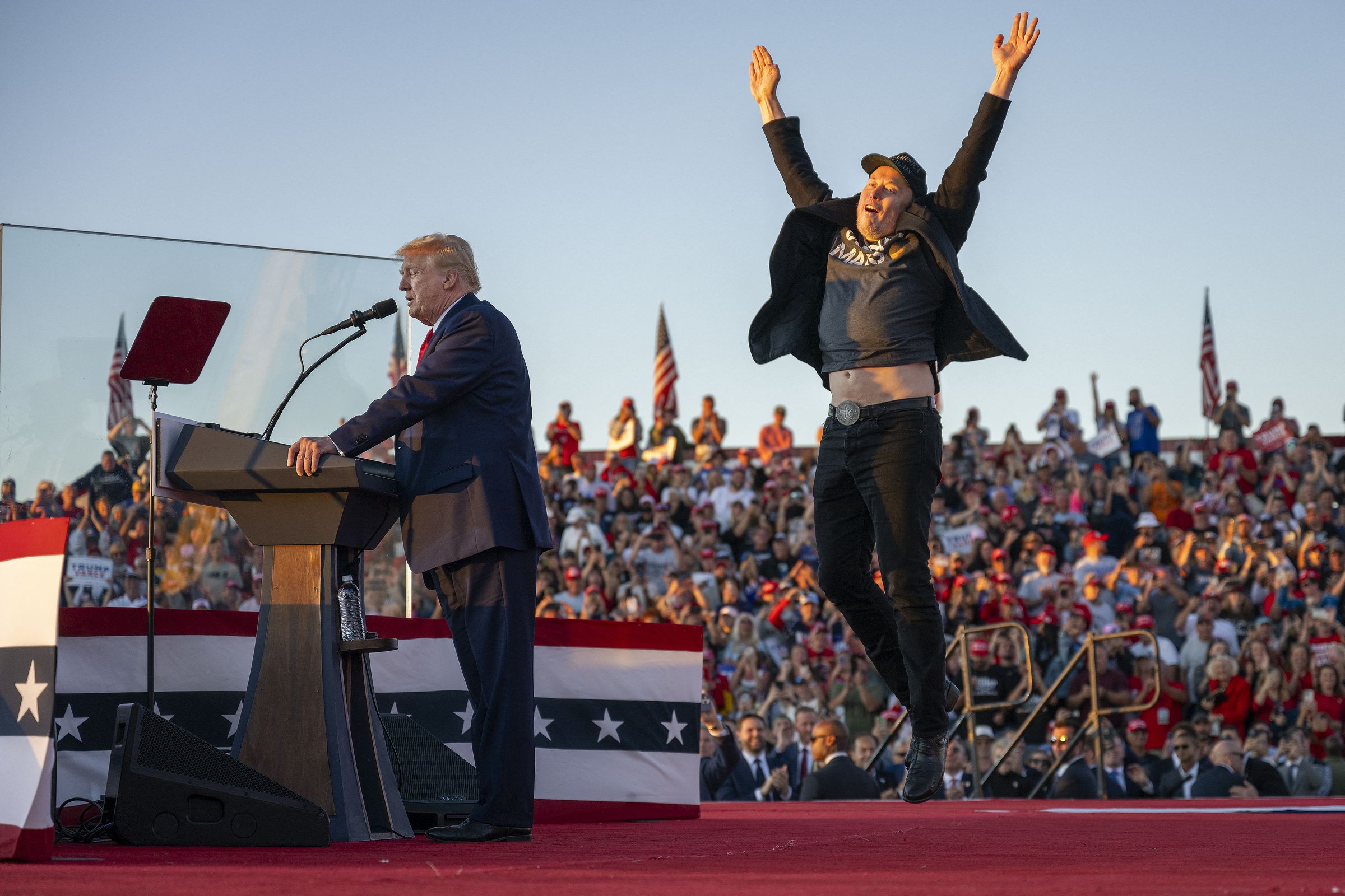 Tesla CEO Elon Musk (R) jumps on stage as he joins former US President and Republican presidential candidate Donald Trump during a campaign rally at site of his first assassination attempt in Butler, Pennsylvania on October 5, 2024.
