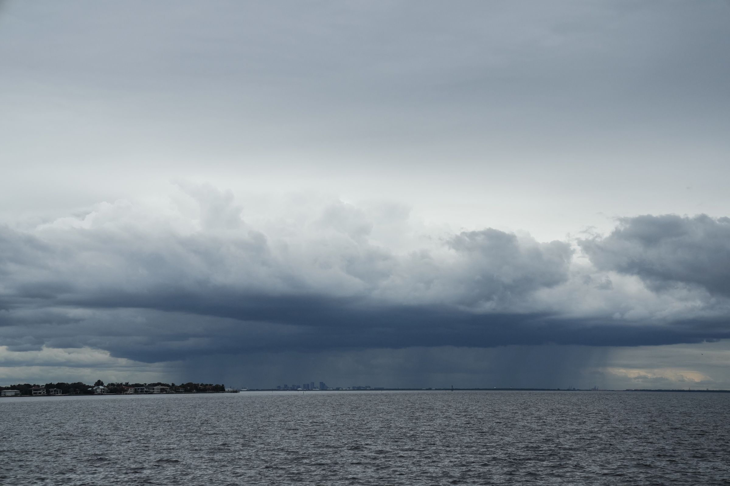 Thunderstorm clouds can be seen moving over open water.