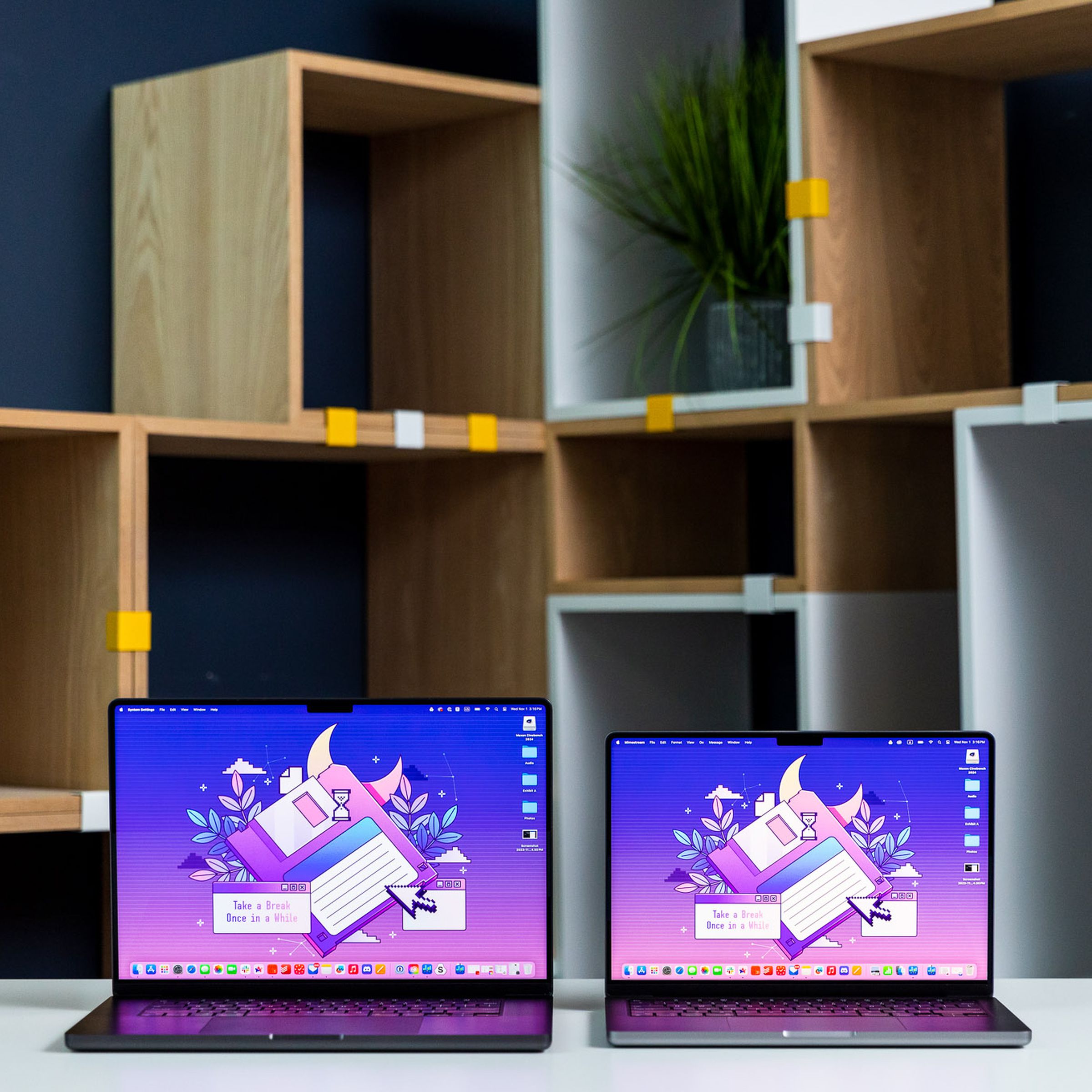 M3 Max MacBook Pro 16 next to an M3 MacBook Pro 14 in front of boxy geometric bookshelves