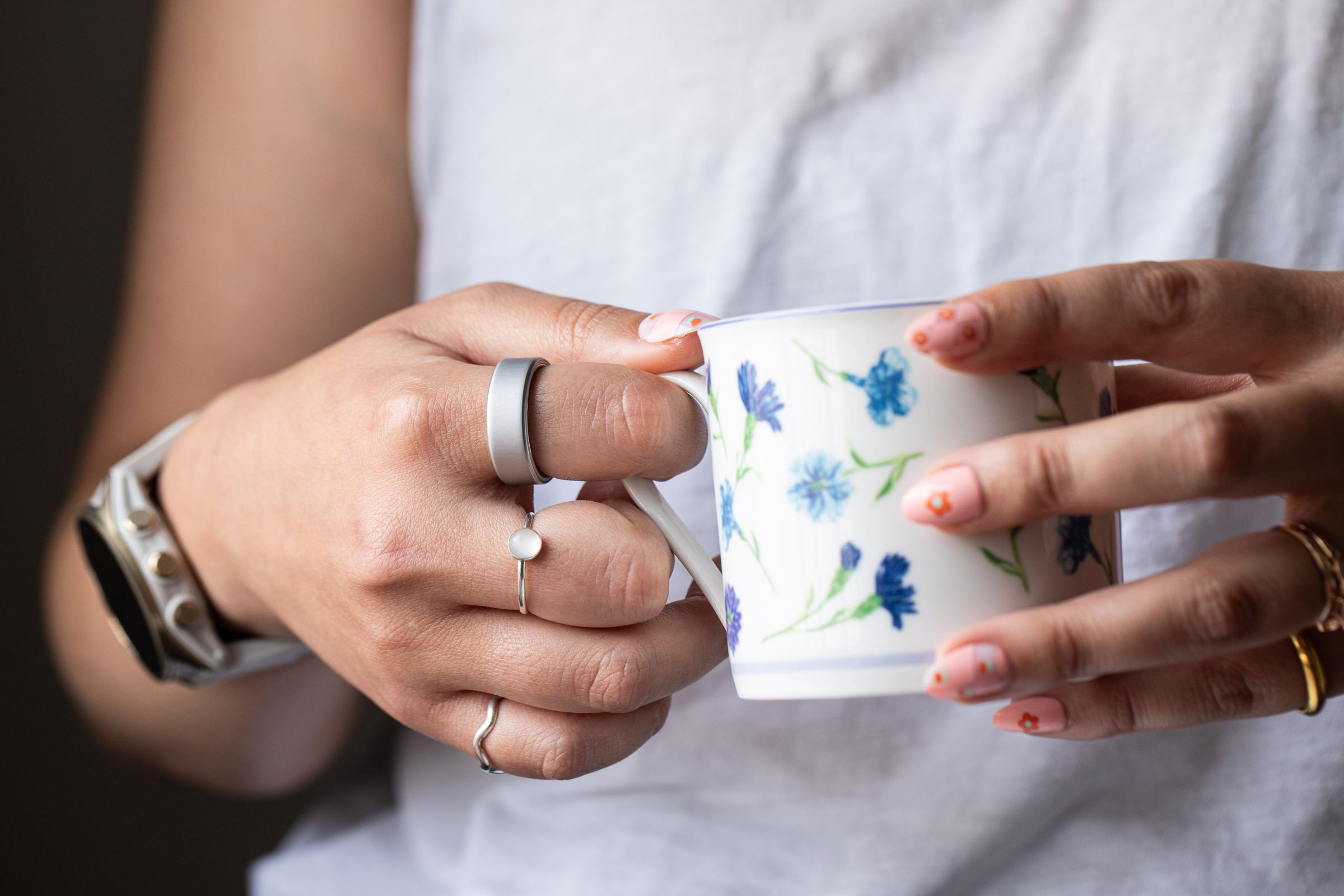 Close up of person wearing Oura Ring while holding a teacup