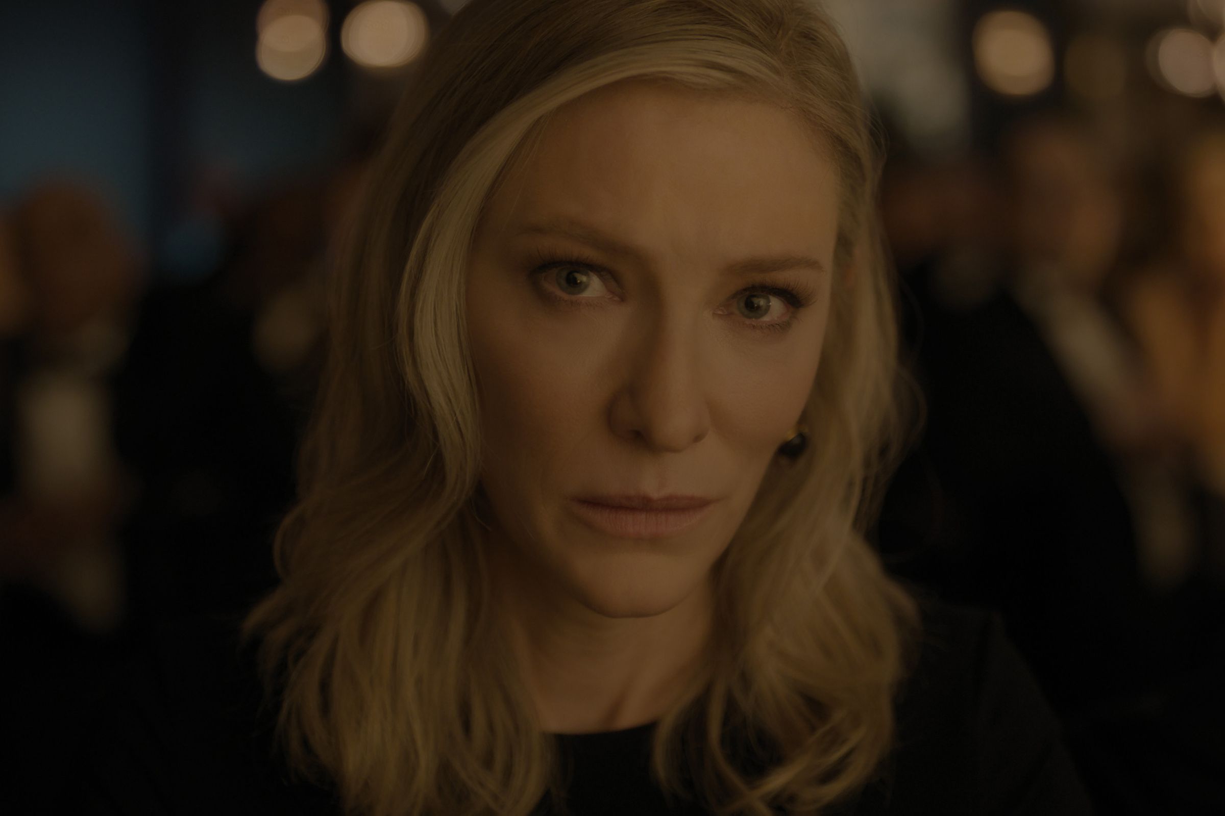 A woman in a black blouse sitting at a dinner table in a restaurant.