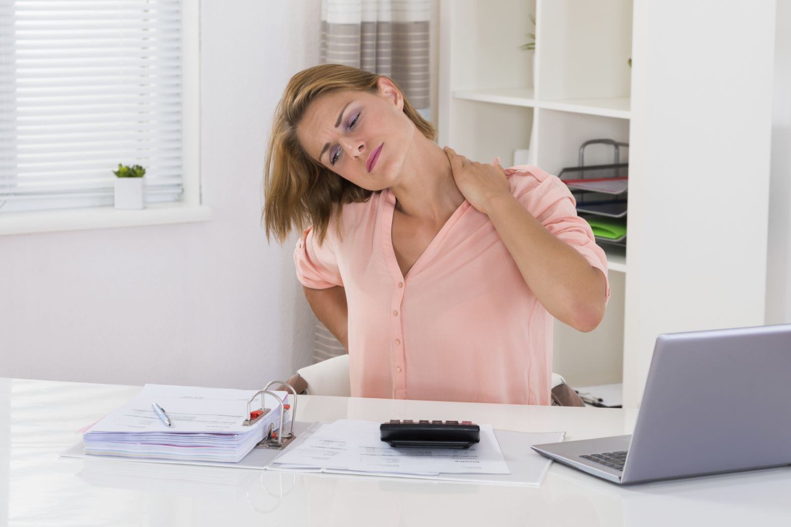 Woman grabs her neck in pain.