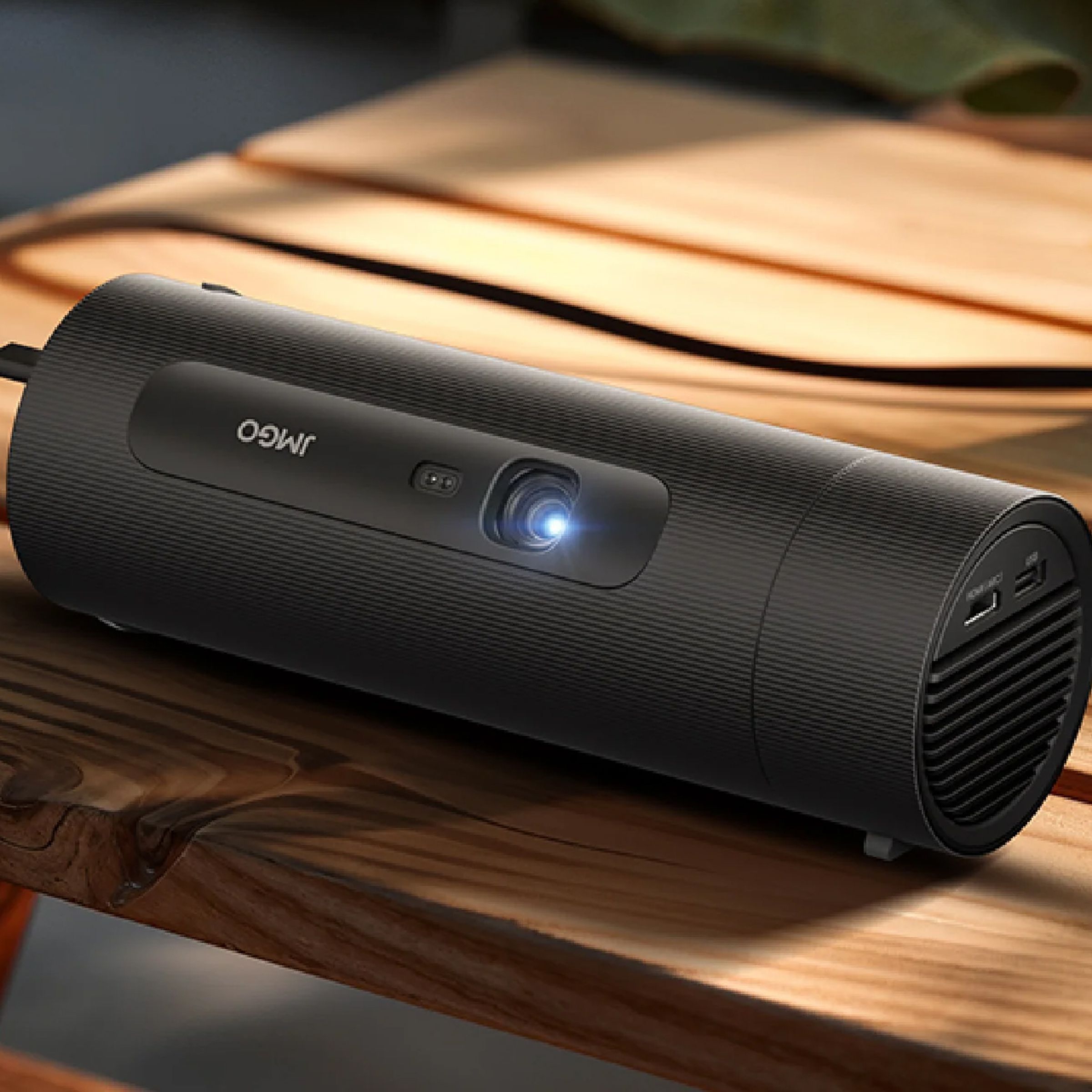 The JMGO Picoflix projector on a wooden picnic table plugged into a battery.