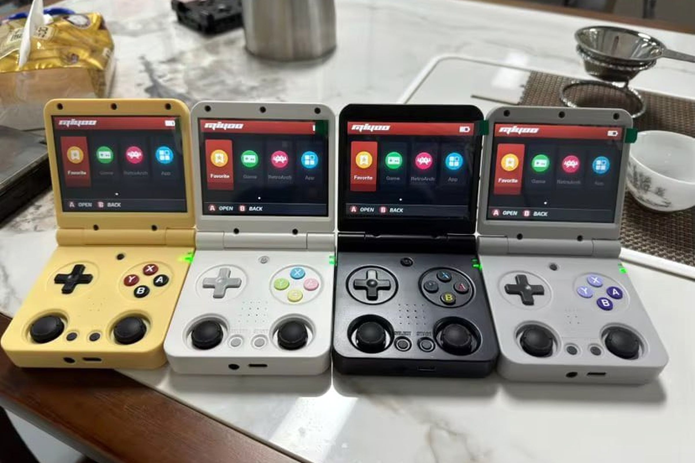 The Miyoo Flip handheld pictured in four different colorways.