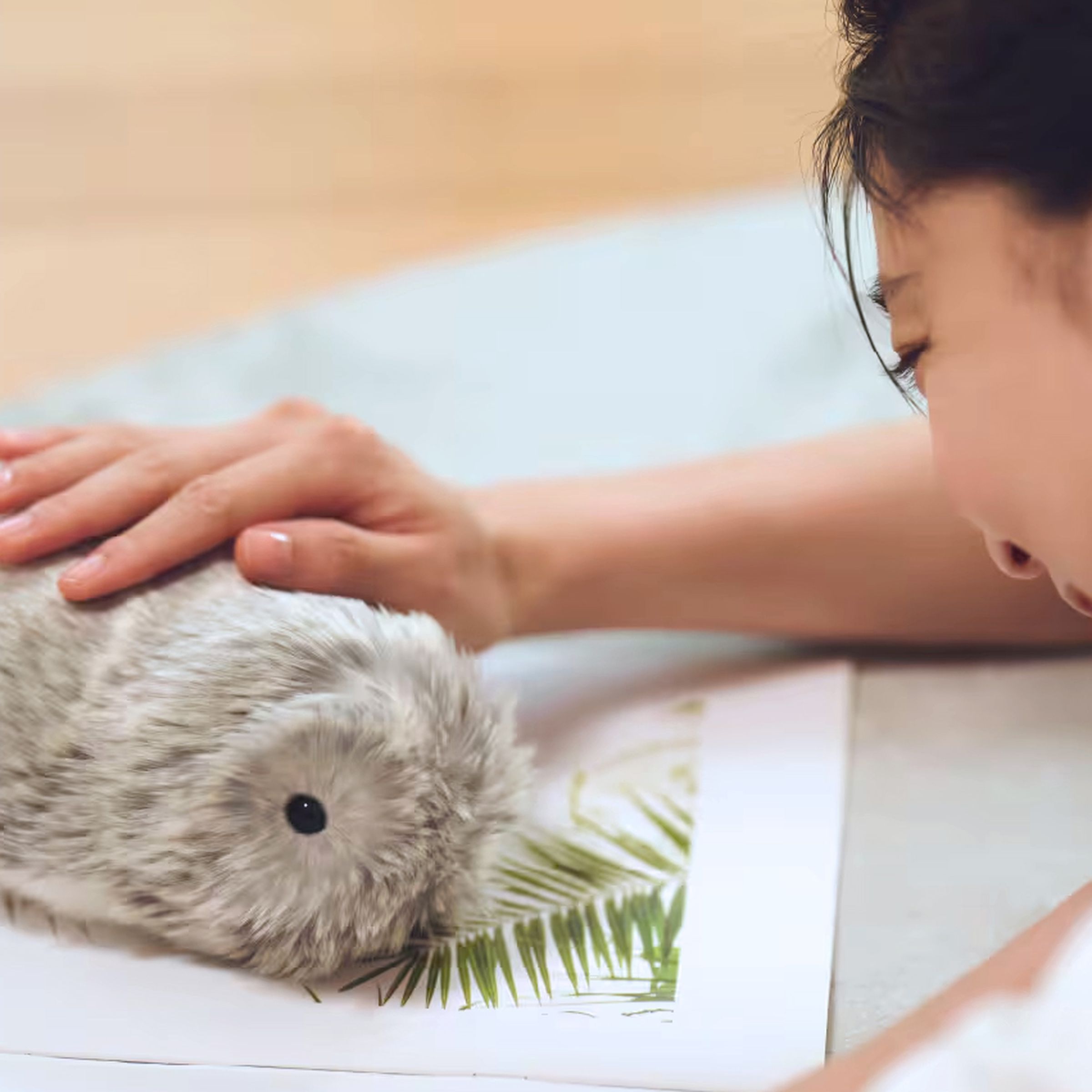 A person pets the top of Casio’s Moflin robotic pet.