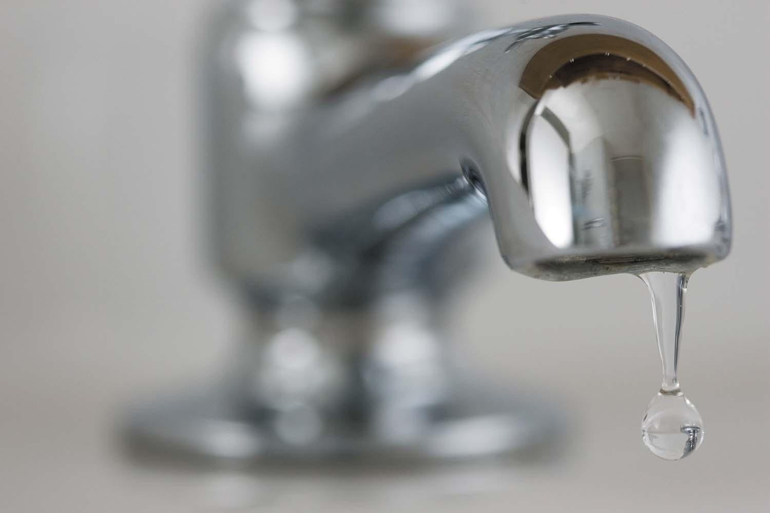 close-up photo of a bathroom faucet, but out of focus; the focus is on water dripping from it