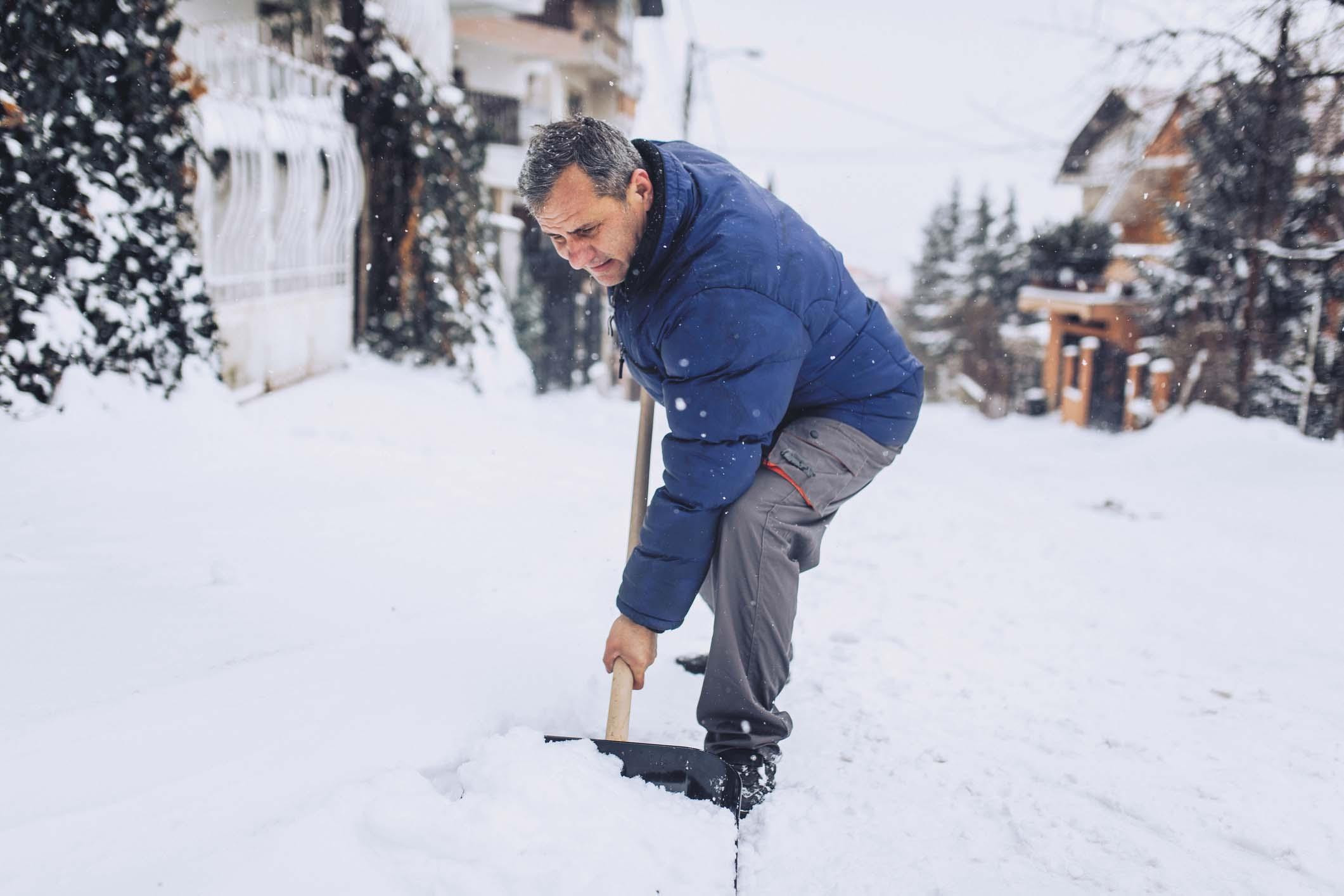 A middle-age man shovels snow.