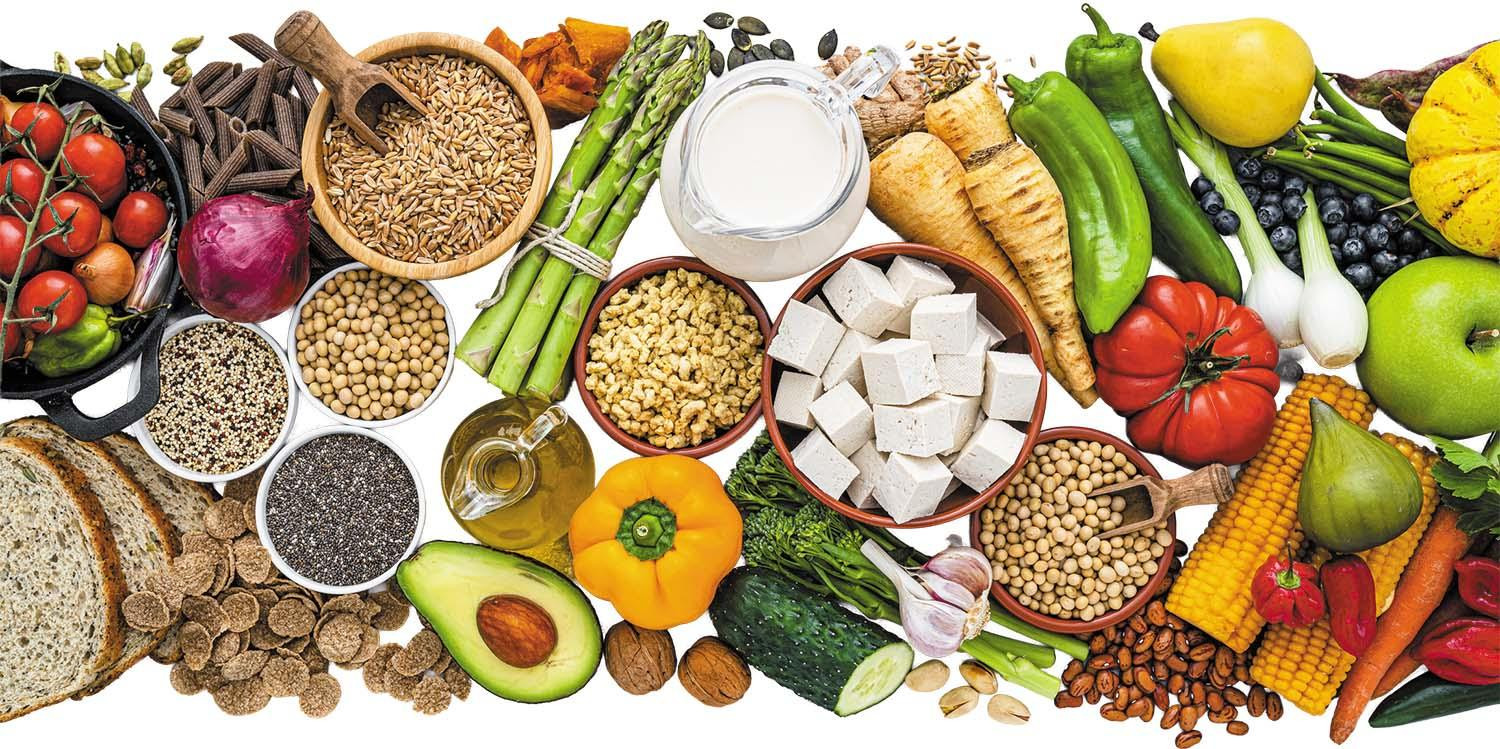 A collage of healthy, plant-based foods including many kinds of fruits and vegetables, tofu, nuts, whole-grain bread, and plant-derived milk.