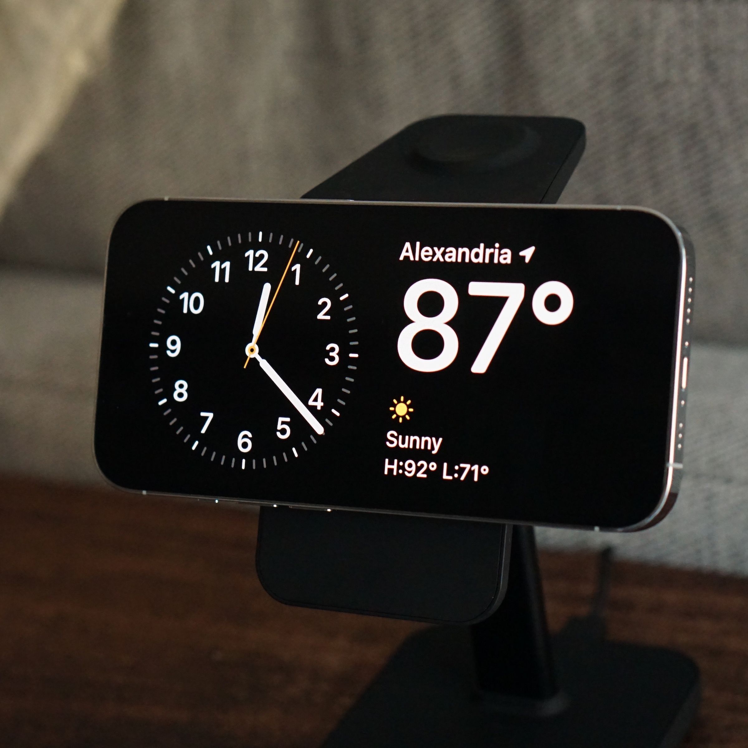 Picture of an iPhone turned sideways on a stand, displaying time and weather information.